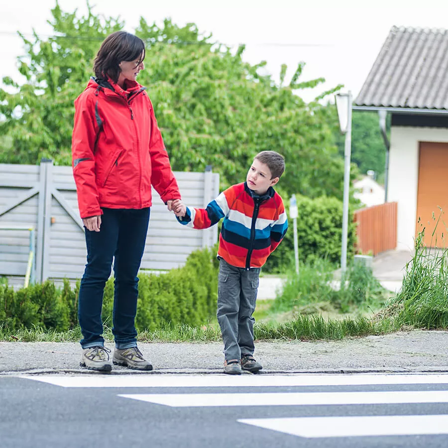 parent holds child's hand at crosswalk